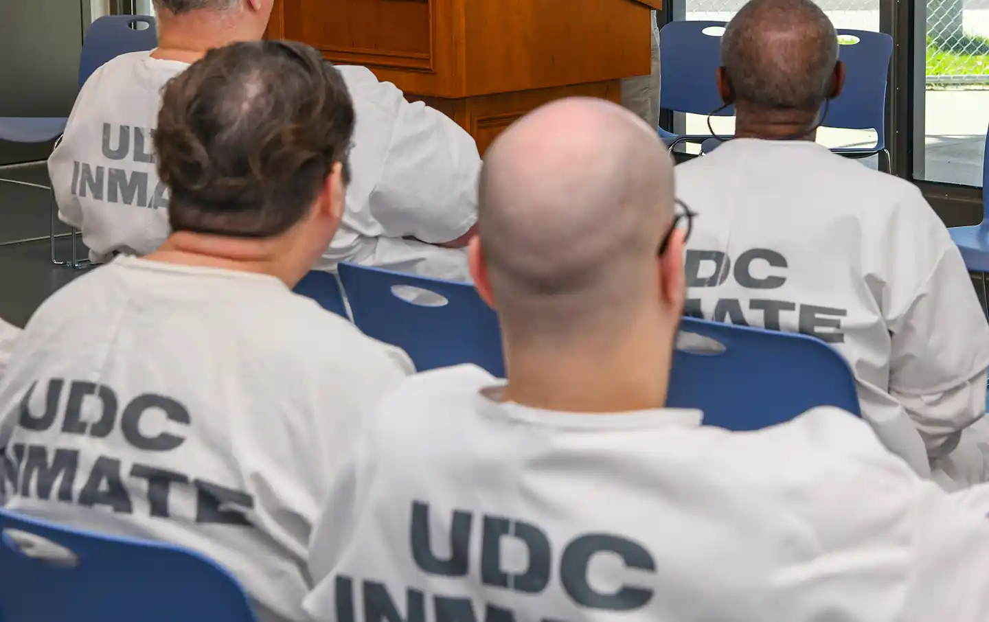 Incarcerated persons sitting in rows, presumably listening to a lecture or class